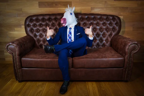Vicces Egyszarvú elegáns ruha ül a kanapén, mint a főnök, és bemutatja a gesztus — Stock Fotó