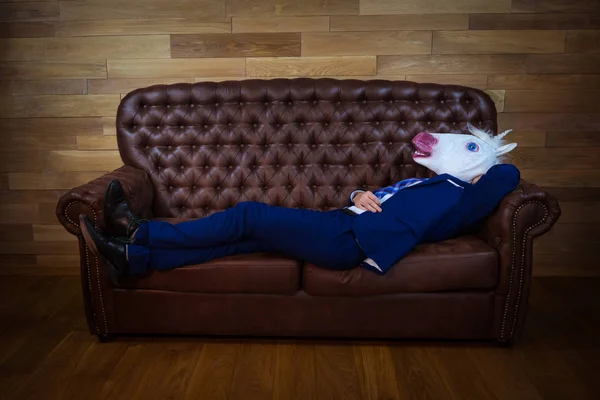Смешной единорог в элегантном костюме лежит на кожаном диване Лицензионные Стоковые Изображения