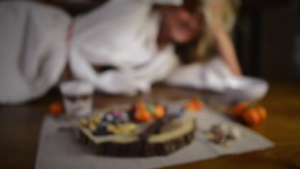 バスローブで満足したブロンドの女の子は パンケーキ フルーツ パフェと木製のトレイの近くのテーブルの上に笑顔 若い眠い女性のクローズアップビュー — ストック動画