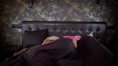 Pijama genç uykulu kadın komik tek boynuzlu at maskesi alışılmadık adam uyanır ve ona sarılır. Garip çift kucaklar ve şık yatak odasında yatakta yatıyor.