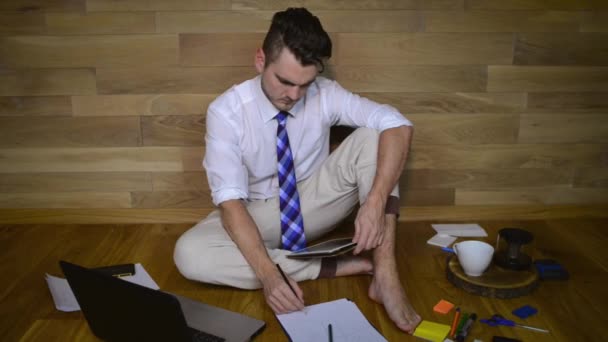 Young Man Works Home Pajama Pants Looking Tablet Makes Notes — Stock Video