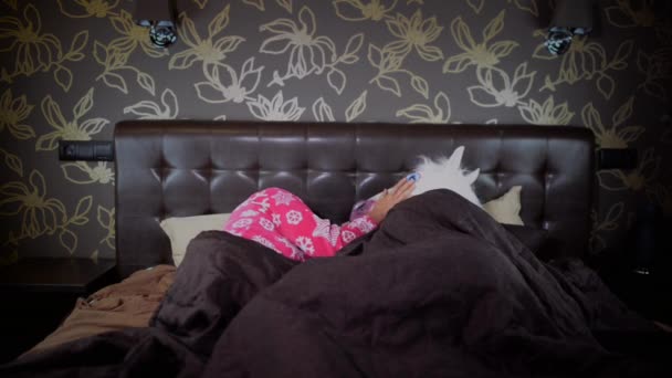 穿着滑稽的独角兽面具的怪人醒了很多次 年轻昏昏欲睡的女人平静不寻常的男人 有趣的夫妇躺在床上在时尚的卧室 — 图库视频影像