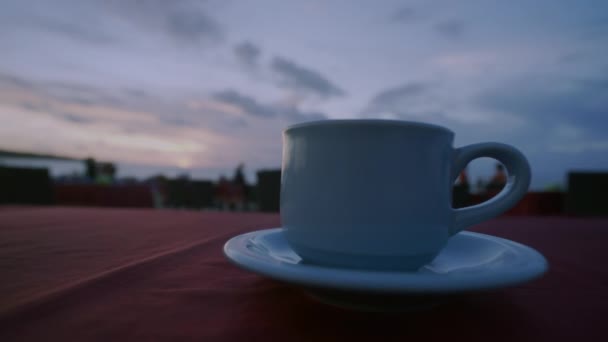 在海滩上喝咖啡或茶 日落时分天空和大海的背景 无法辨认的人四处走动 人手拿杯子 站起来 — 图库视频影像