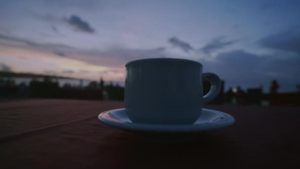 在海滩上喝咖啡或茶 日落时分天空和大海的背景 无法辨认的人四处走动 女服务员把蜡烛放在桌子上 — 图库视频影像
