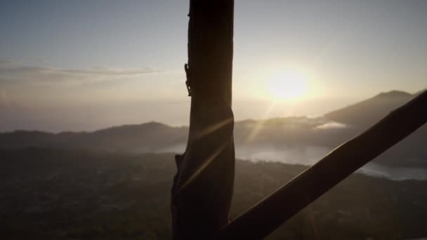 早朝に木造建築物に太陽光線が落ちる 日の出 下の村や植物の火山の頂上からの美しい景色 旅行先 インドネシア — ストック動画