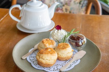 Çay ve çöreğin tadını çıkarırken veya reçelli çörekler ve krema yerken