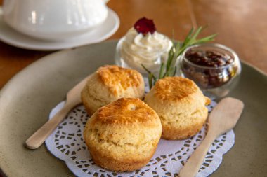 Çay ve çöreğin tadını çıkarırken veya reçelli çörekler ve krema yerken