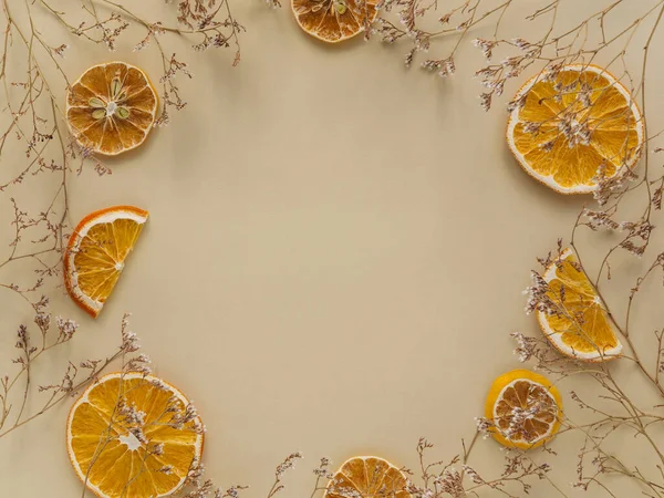 Circle of dried flowers and orange slices. Space for text.