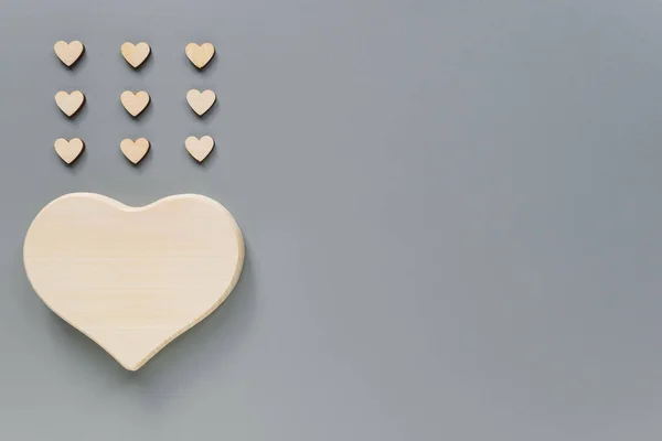 Mock-up of a wooden big heart and small hearts for Valentine\'s day. Hearts in the form of rain. Wooden hearts on a grey background with Kopi space.