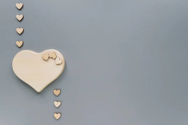 Hearts of different sizes made of eco-friendly materials. Wooden hearts for Valentine's Day. Hearts on a grey background with copy space.