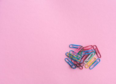 Açık mor arka planda çok renkli ataçlar, okul veya iş için kırtasiye malzemesi