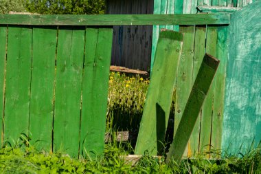 Kırık tahtaları olan eski yeşil ahşap çitler. Kırsal görünüm.