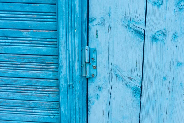 door hinge screwed to a bright painted old wooden door