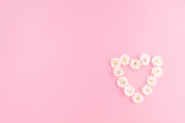 Çiçek kompozisyonu. Pembe arka planda beyaz küçük gülün kalp çerçevesi. Anneler günü, sevgililer günü, doğum günü, bahar, yaz konsepti. Düz konum, üst görünüm, kopyalama alanı