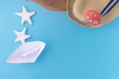 Beyaz kağıt tekne, deniz yıldızı ve mavi arka planda kum. Seyahat ya da tatil kavramı.