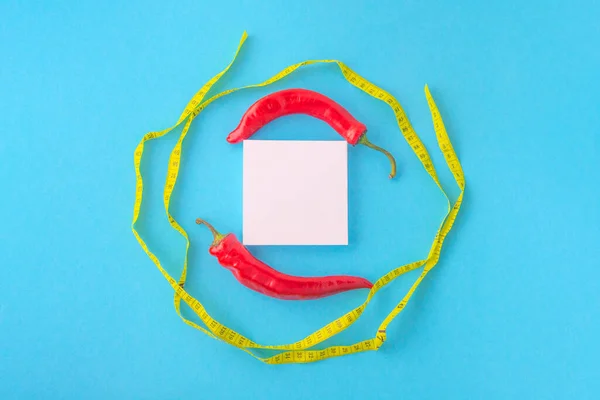 Pimientos rojos, blanco en blanco y cinta métrica sobre fondo azul — Foto de Stock