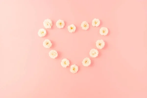 Flowers composition. heart frame of white small rose on pink background. Mother\'s day, Valentine\'s day, birthday, spring, summer concept. Flat lay, top view, copy space