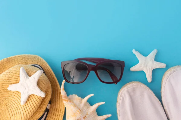 Yaz tatili ve plaj tatili. Hasır şapka, mavi arka planda denizyıldızı. Seyahat ya da tatil kavramı.