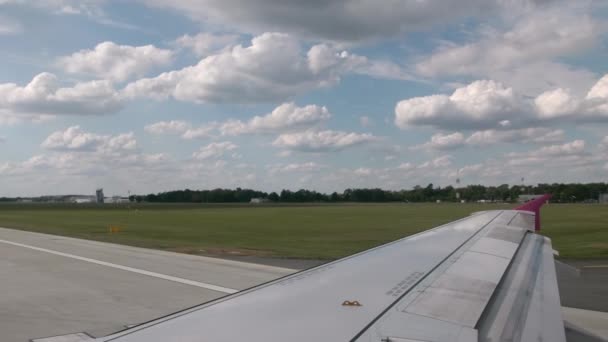 Das Flugzeug auf dem internationalen Flughafen auf der Landebahn manövrieren. Ego-Blick aus dem Cockpit des Flugzeugs, im Rahmen ein grauer Flügel mit einer pinkfarbenen Flügelspitze. im Hintergrund befindet sich die — Stockvideo