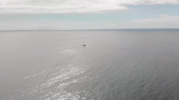 Disparo aéreo. Un yate de vela solitario navegando a través de las aguas azules del océano. Contra el cielo azul. El concepto de recreación activa en el agua y el yate. Islas Canarias, Tenerife — Vídeos de Stock