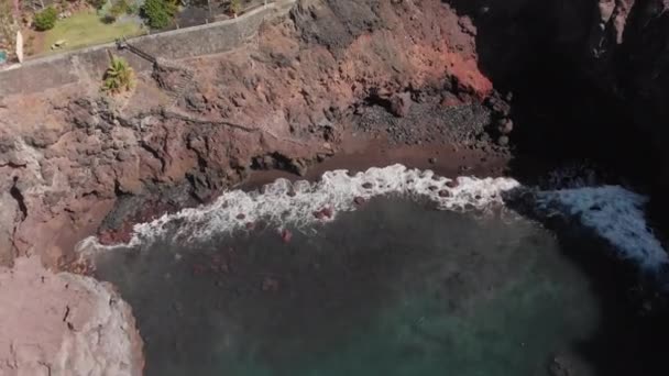 Tir aérien. rivage volcanique rocheux sur lequel battent les vagues bleues de l'océan. Dans le cadre des installations terrestres et des escaliers pour les touristes. Îles Canaries, Tenerife, Los Gigantos 