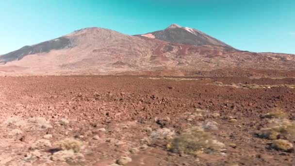 Aerial drone shooting. Desert volcanic Martian landscape in red. Stones and a mountain with a volcano against the blue sky. The concept of colonization and relocation to Mars and other planets. Low — Stock Video