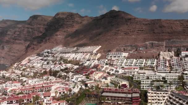 Antenn skott. Solig dag över den turist bergsstaden med många hotell ligger på berget. Mountain road serpentin hårnål där bilarna går. Kanarieöarna, Teneriffa, Los Gigantos — Stockvideo