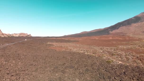 Antenowe. Wyspy Kanaryjskie, wulkan Teide. Park narodowy. Droga z Jazda samochodów w górskiej dolinie na tle czerwonej góry i błękitne niebo. Pojęcie kolonizacji i przeniesienie do — Wideo stockowe