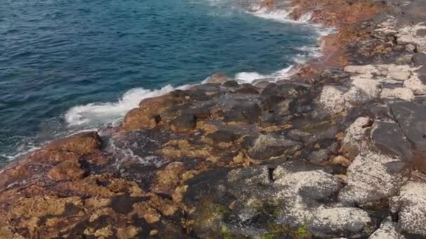 Vue aérienne. Surf de mer, vagues circulaires tournantes éclaboussant bleu et turquoise en couleur et littoral volcanique de pierres et de lave fossile séchée, Ténérife, îles Canaries, Espagne. Dolly gros plan Mer — Video