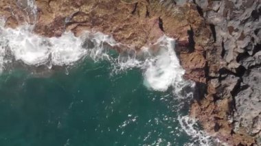 Hava atış. Dikey plan. Mavi Dalgalar sıçramasına ve Turkuaz rengi ve volkanik kıyı şeridi taşlar ve kurutulmuş fosil lav, deniz köpüğü, Tenerife, Kanarya Adaları, İspanya. yakın çekim