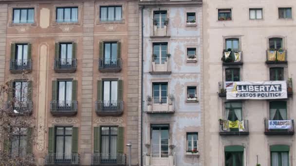 БАРСЕЛОНА, Испания - февраль 2019 года. Средний выстрел. Квартал в Барселоне с балконом, на котором висит флаг Каталонии, желтая лента и плакат протеста. Концепция сепаратизма и — стоковое видео