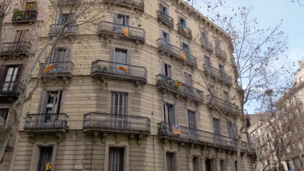 БАРСЕЛОНА, Испания - февраль 2019 года. Осенняя панорама дома в Барселоне с балконами, на которых размещены флаги Каталонии. Концепция сепаратизма и отчуждения от Испании в Каталонии — стоковое видео