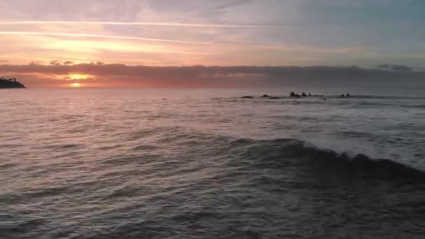 Un disparo aéreo. Salida del sol sobre el océano. El sol apareció sobre el horizonte. Colores rosa y naranja. Ocean Island, Olas salpicadas de piedras volcánicas de lava congelada que sobresalen del agua. El concepto — Vídeos de Stock