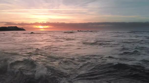 Colpo aereo. Alba sopra l'oceano e la spiaggia vulcanica sull'isola. Oceano surf e il sole è apparso sopra l'orizzonte. Colori rosa e arancio. Onde spruzzate su pietre vulcaniche di lava ghiacciata che — Video Stock