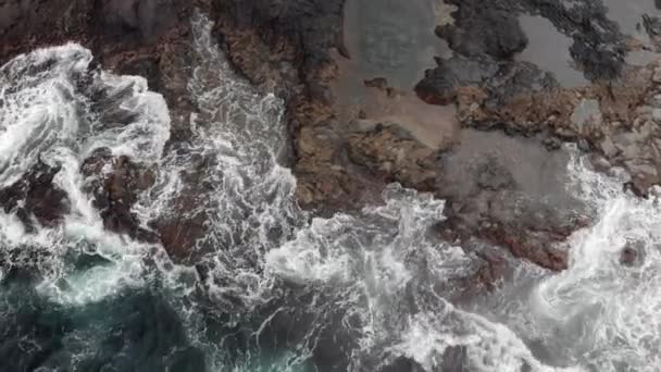 Vista superior. Piscinas naturales, costa volcánica empinada, arrecifes de lava volcánica congelada, océano Tormentoso, espuma blanca de las olas gigantes que golpean la costa. Un disparo aéreo. Garachico, Tenerife, Islas Canarias — Vídeos de Stock