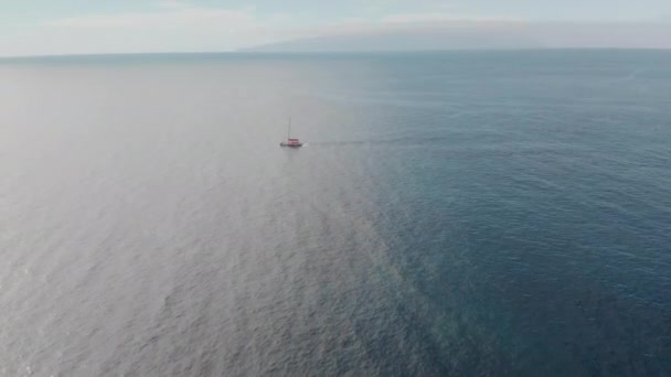 Disparo aéreo. Iate à vela solitário nas águas azuis do oceano. Contra o céu azul. O conceito de recreação ativa na água e iatismo. Ilhas Canárias, Tenerife — Vídeo de Stock