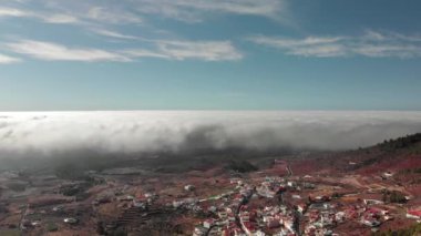 Hava atış. Güzel bir dairesel uçuş hacimsel doku fırtına bulutların üzerinde kırmızı bir volkanik vadi üzerinde. Aşağıda küçük bir kasaba, beyaz ve kırmızı çatılar, dağ yolları boyunca ile bir köy olduğunu