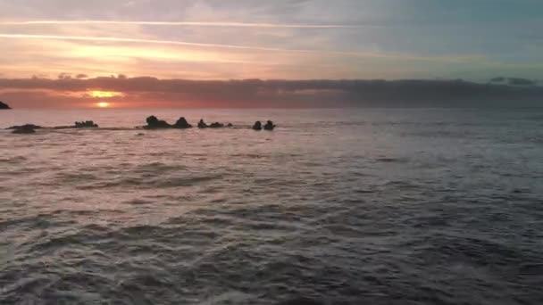 Letecký snímek. Východ slunce nad oceánem. Slunce se objevilo nad obzorem. Růžové a oranžové barvy. Ocean Island, úvodní vlny na vulkanické kameny zmrazených lávy, které vyčnívají z vody. Koncept — Stock video