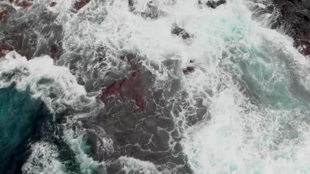 顶部视图。陡峭的火山海岸, 冰冻的火山熔岩的珊瑚礁, 狂风暴雨的海洋, 来自海浪冲击海岸线的白色泡沫。空中射击。加拉奇科, 特内里费岛, 加那利群岛。的概念。 — 图库视频影像