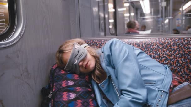 慢动作年轻美丽的女孩在眼罩上的眼睛, 在地铁列车上睡着了。头戴在背包上。火车到达车站。疲劳的概念, 对睡眠的渴望 — 图库视频影像
