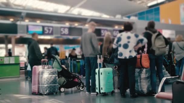 Slow Motion Unrecognized Family tourist grandmother with her teenage grandson, waiting in line for check-in at the international airport terminal. With suitcases of different colors — Stock Video