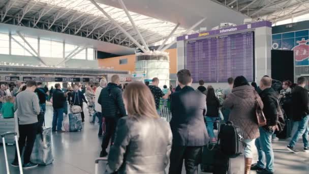 乌克兰基辅-2018年10月2日。慢动作国际机场巨大的信息板。他周围是不被认出的、模糊的游客和带着行李箱的旅客。等待出发和 — 图库视频影像