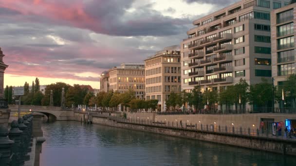 Sunset in the center of the capital. River near the island of museums. Pink multicolored clouds. Light comes on in the houses. slow motion — Αρχείο Βίντεο