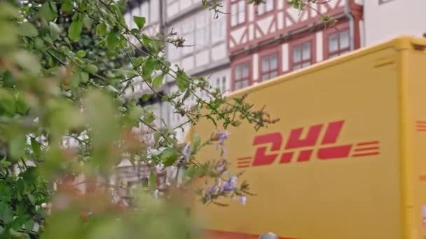 HANOVER, เยอรมนี - ตุลาคม 2018 รถตู้ขนส่งสินค้าสีเหลืองของบริการจัดส่งของ DHL ขี่ผ่านเมืองกับพื้นหลังของต้นไม้สีเขียว กับพื้นหลังของถนนของ — วีดีโอสต็อก