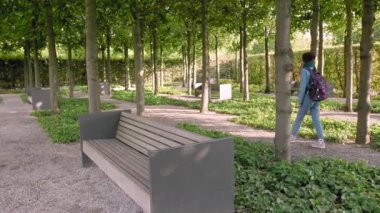 Hannover, Almanya. Elinde bir harita ve bir sırt çantası ile genç bir kadın turist gün batımı nda parkın sokaklarında yürüyor. Çerçeve içinde ağaçlar ve taş banklar bir sürü. Geri gider