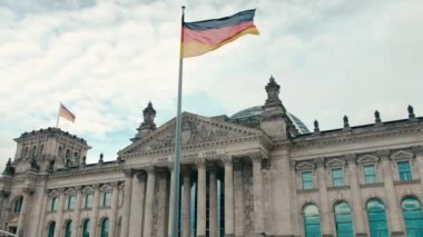 Yavaş Hareket Başkent Berlin'in merkezinde Bundestag-parlamento binasının arka planına karşı Almanya bayrağı. Mavi huzurlu gökyüzünün arka planına karşı