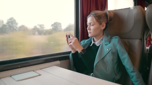 Giovane donna d'affari caucasica è in viaggio in una carrozza treno intercity di lusso. Utilizza un telefono cellulare per le foto. Rallentatore — Video Stock