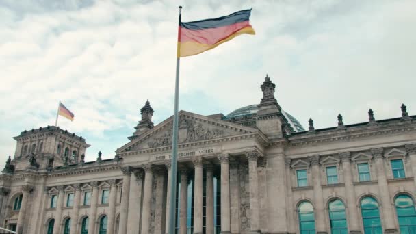 In Zeitlupe weht die Deutschlandfahne vor dem Hintergrund des Gebäudes des Bundestages im Zentrum der Hauptstadt Berlin. vor dem Hintergrund des blauen, friedlichen Himmels
