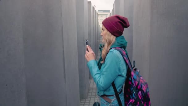 Berlin, Németország-október 2018: Slow Motion kaukázusi lány turista egy hátizsák közepén Berlin az őszi. Az emlékmű fotóját okostelefonra teszi az Európai meggyilkolt zsidóknak. A — Stock videók