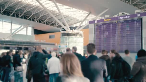 กระดานข้อมูลขนาดใหญ่ที่สนามบินนานาชาติ รอบตัวเขาไม่รู้จักนักท่องเที่ยวเบลอและนักท่องเที่ยวพร้อมกระเป๋าเดินทาง รอการออกเดินทาง ยูเครน, คีฟ — วีดีโอสต็อก